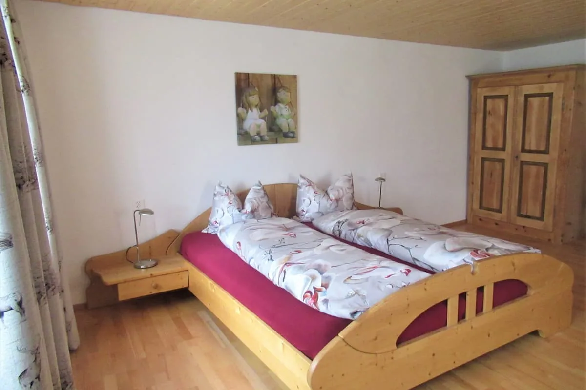 Gästezimmer mit zwei zusammengestellten Holzbetten, Nachttischen und einem bemalten Schrank.